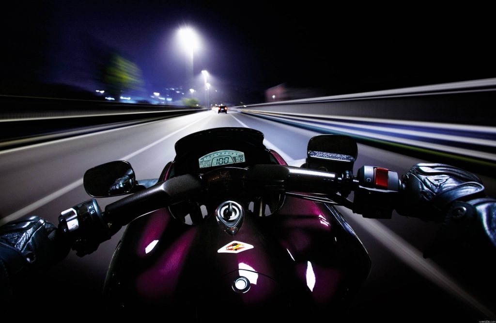 Pilotage d'une moto de nuit sur une route éclairée