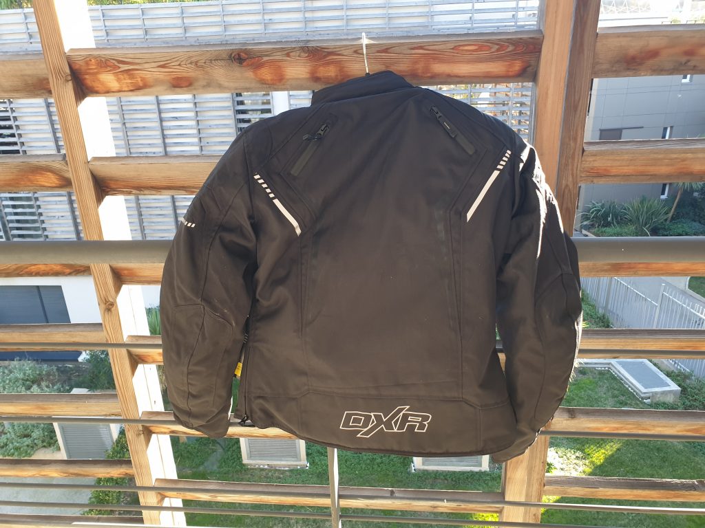 Vue d’ensemble sur le dos du blouson DXR Julia CE : logo en bas, bandes réfléchissantes et zips d’aération.