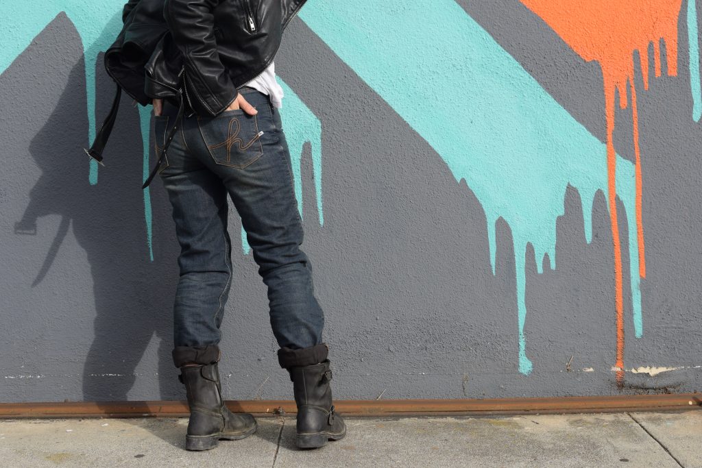 motarde posant devant un mur graphé avec un jean moto