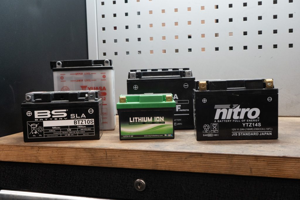 Différentes batteries moto posées sur un établi