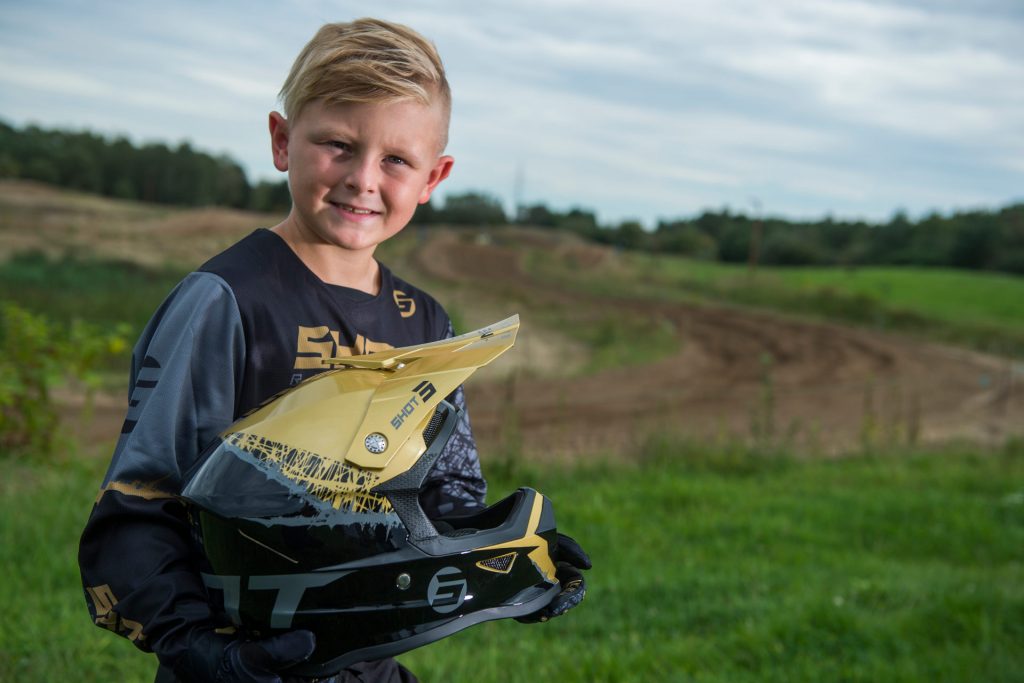 Un enfant portant à bout de bras un casque moto cross léger