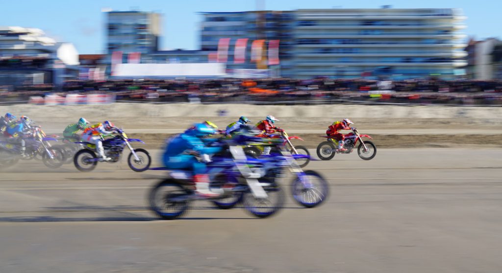 Pilotes de l'Enduropale couchés sur leur motocross sur la plage après le départ