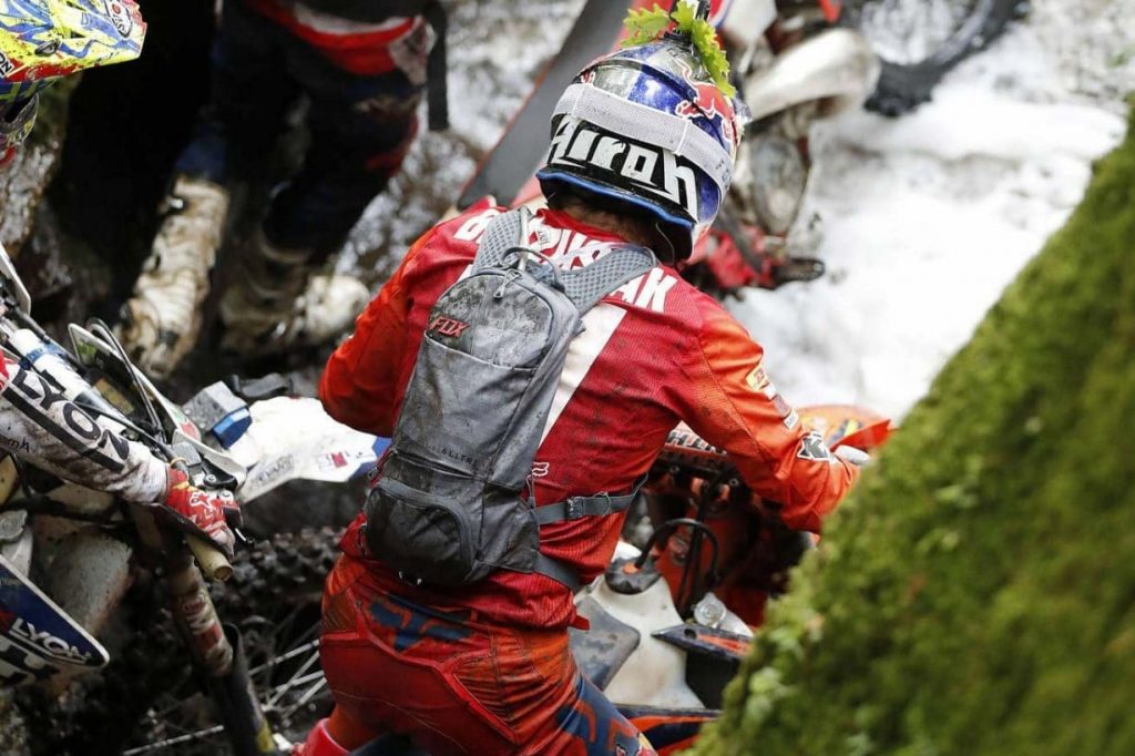 Piloto de enduro de espaldas llevando una mochila de hidratación