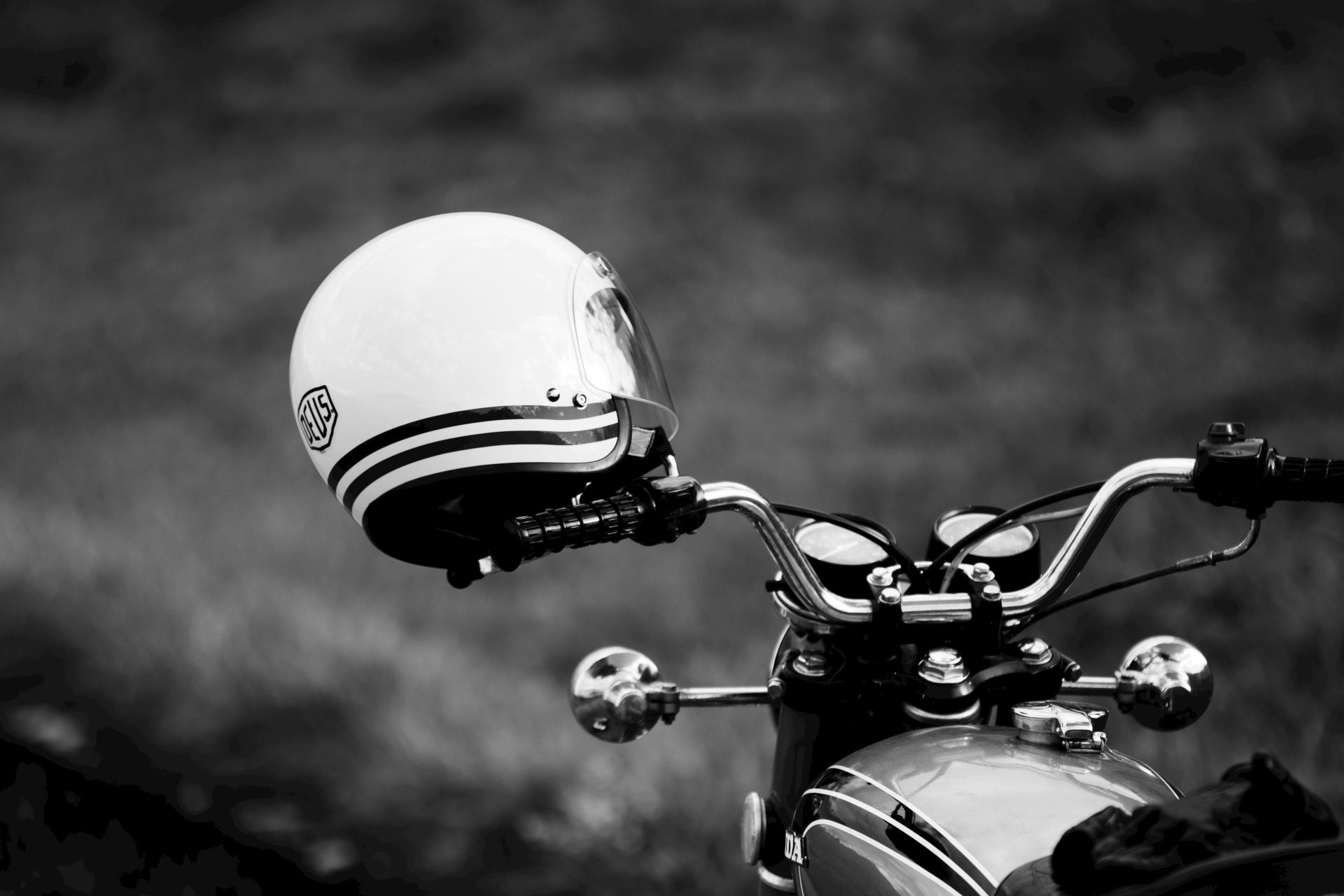Casco jet colgado del retrovisor de una moto vintage, foto en blanco y negro