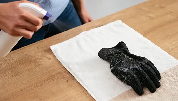 Spray déperlant pulvérisé sur un gant moto textile