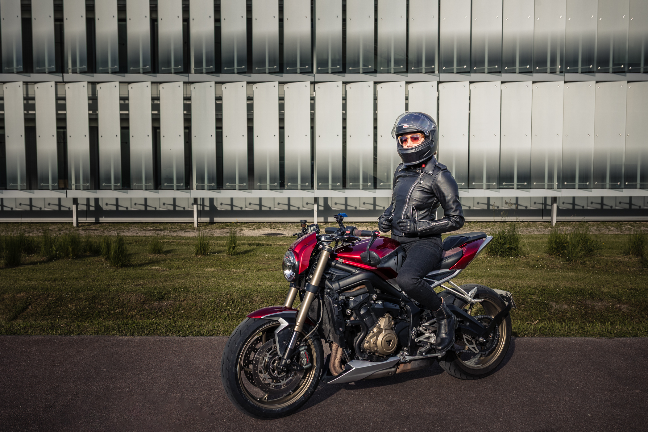 Alyson sur sa moto rouge, posant en équipement avec la veste DXR Jude EVO